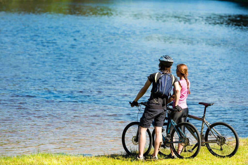 Young cyclist couple standing and watching the lake