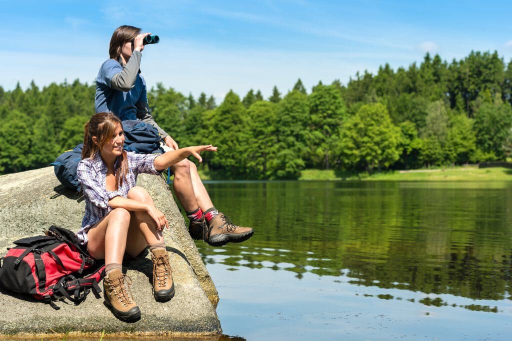 Caucasian teenage hikers birdwatching at lake