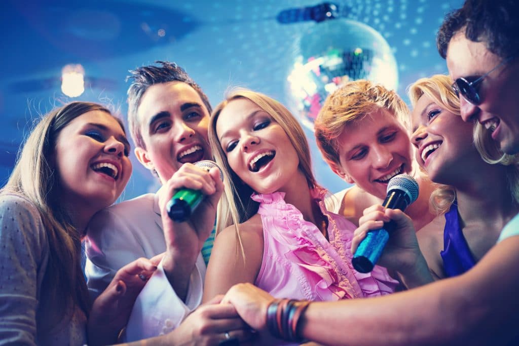 Portrait of joyous guys and girls singing at party together