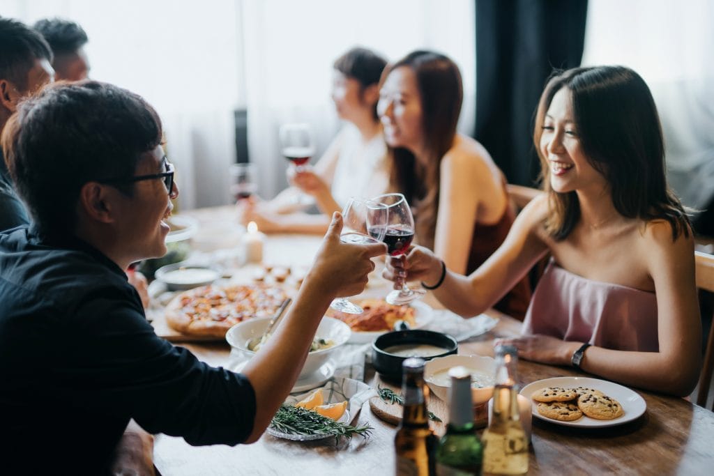 Group of joyful young Asian man and woman having fun and toasting with red wine during party