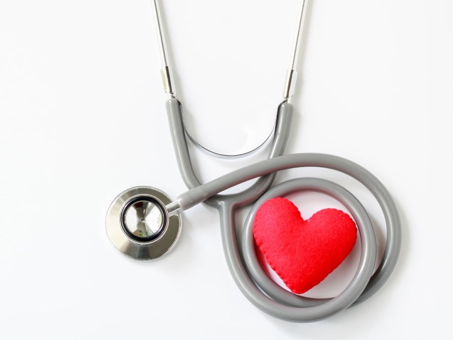 Gray stethoscope with red heart isolated on white background. Medical instruments used to hear sounds within the patient's body. Top view.