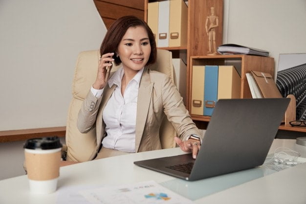 a business woman making a call and using a laptop