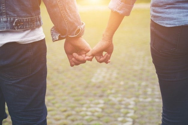 a couple holding fingers in the sunlight