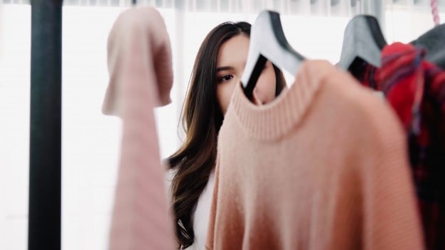 a woman selecting from a wardrobe of clothes