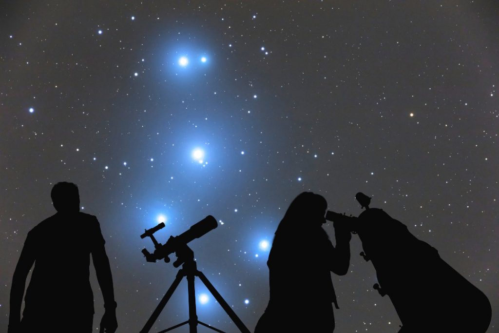 Couple looking at the stars with telescopes. 