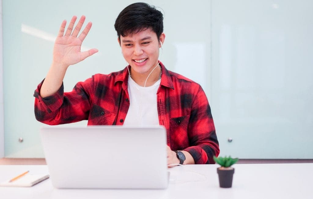 close up young asian student man wearing earphone and greeting on video conference with friends or family in relax time , technology lifestyle concept