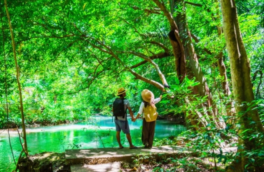 Travelers, couples with natural travel backpacks during the holidays. Couples traveling, relaxing in greens jungle and enjoying the beautiful Emerald pond. Tourism, hiking, nature study. (Travelers, couples with natural travel backpacks during the ho