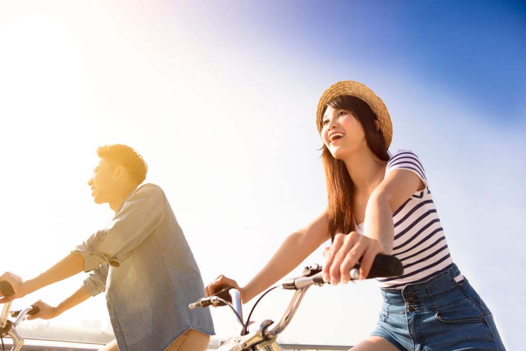 Happy young couple going for  bicycle ride on a sunny day